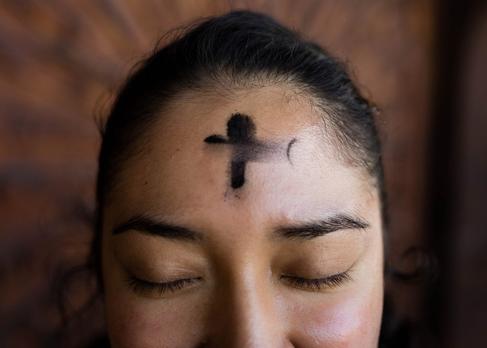 women with ashes in the shape of a cross on her forehead