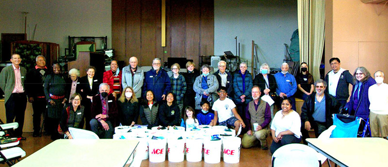 group of multi generational volunteers posing with the buckets they assembled to help flood victims