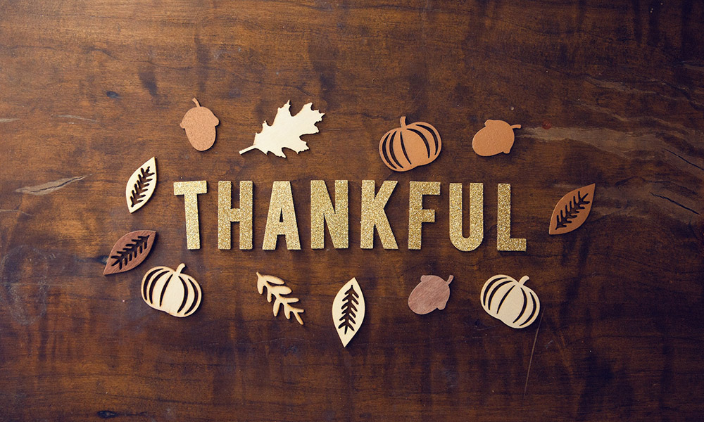 the word thankful with paper cut out pumpkins and leaves