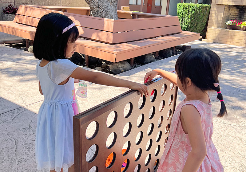 two children playing connect four on the church patio